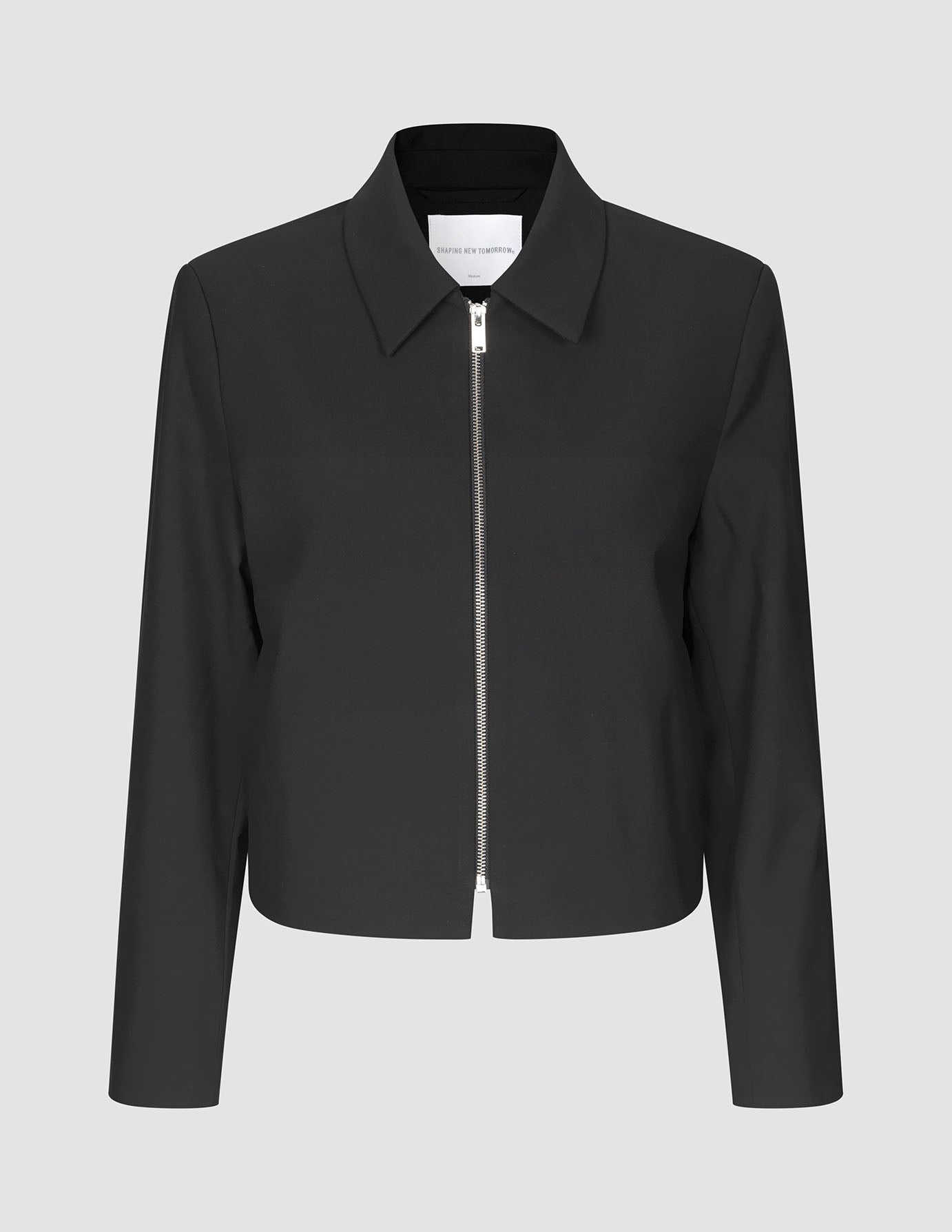 Essential Short Zip Jacket Black: en minimalistisk, kort svart jacka med en helsilverfärgad dragkedja framtill.
